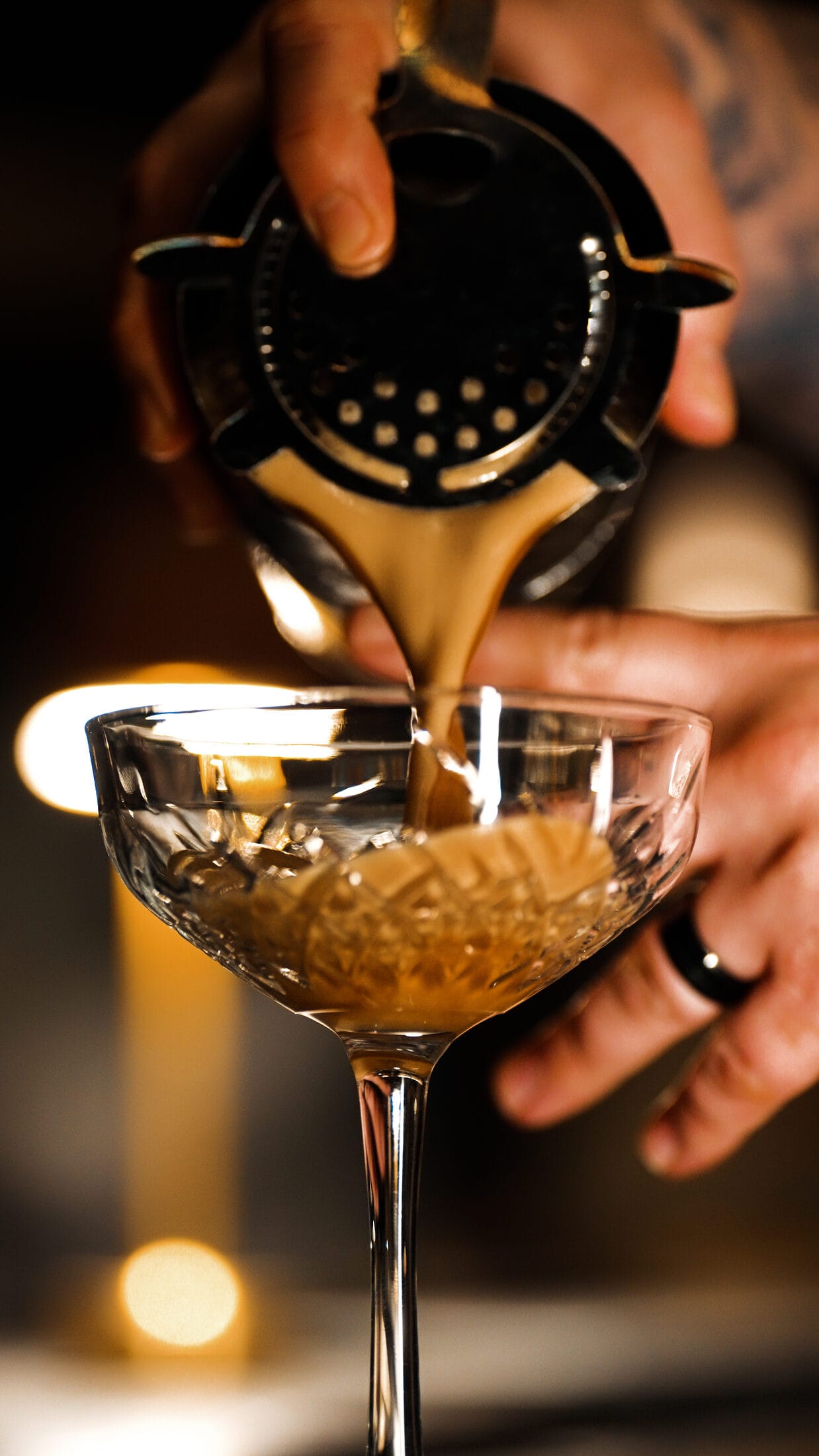 A cocktail poured into a coupe over candlelight at Ember & Eagle