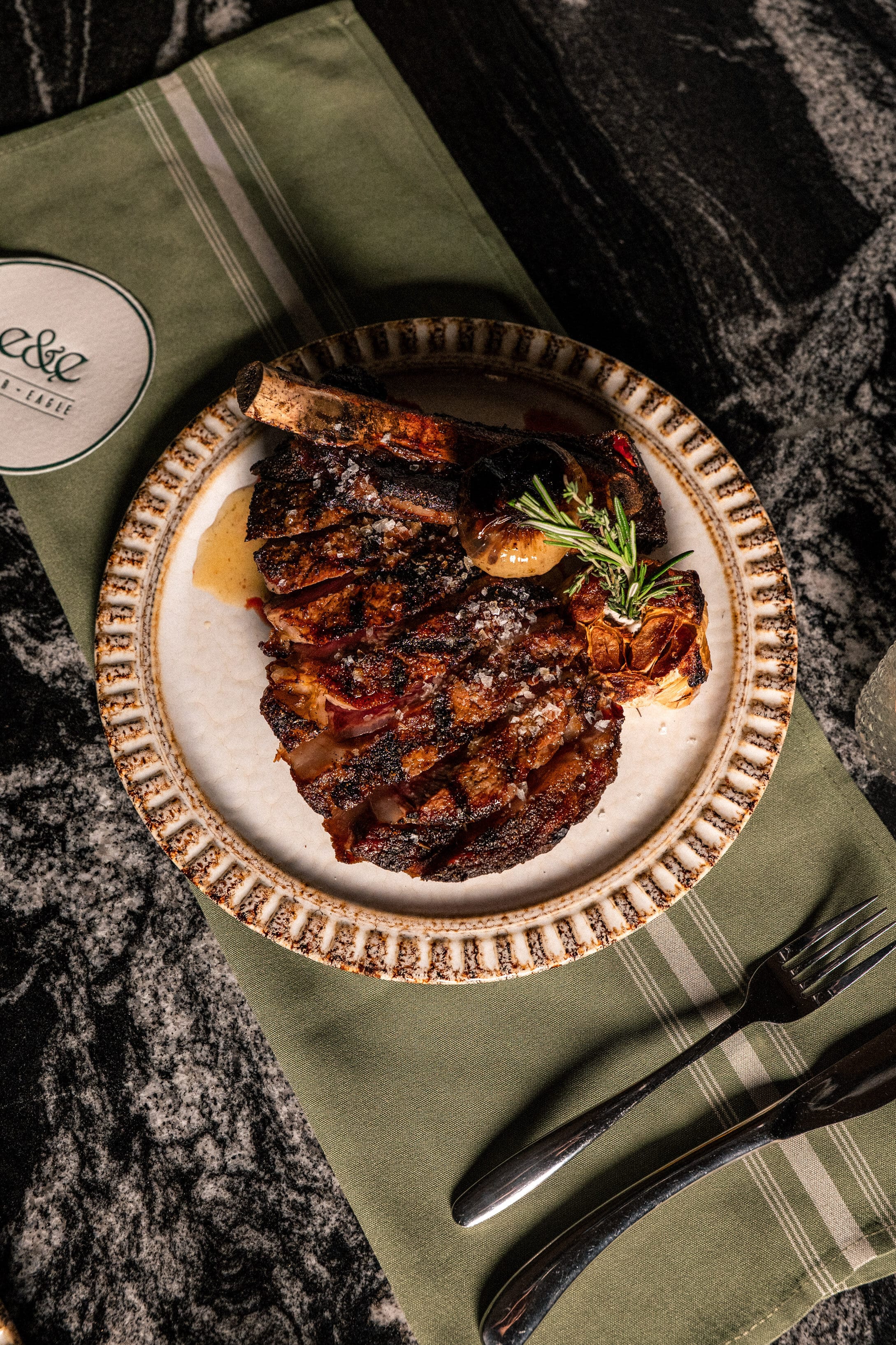 A sliced prime dry-aged steak plated at Ember & Eagle