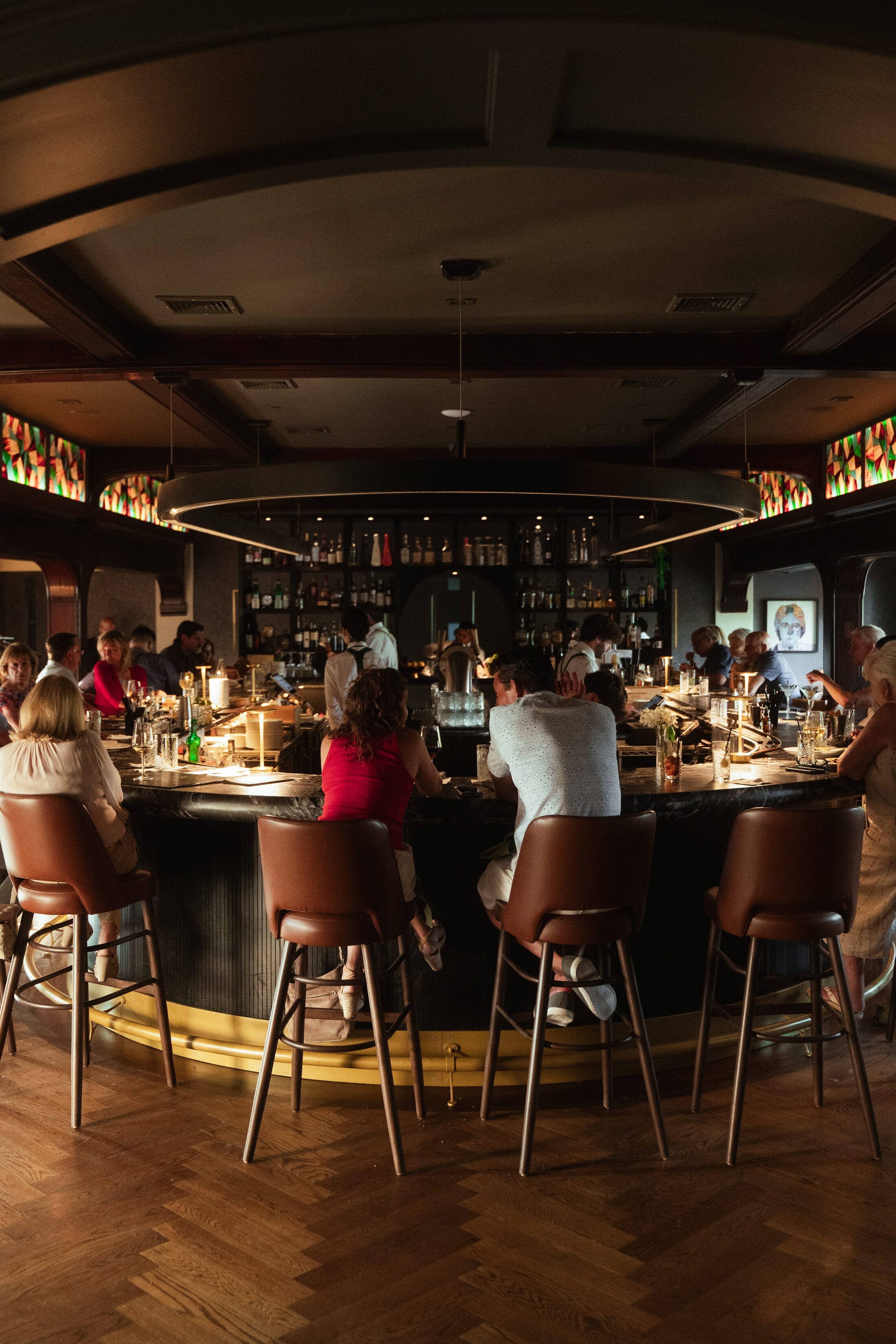 Guests gathered around the curved Parlor Bar at Ember & Eagle